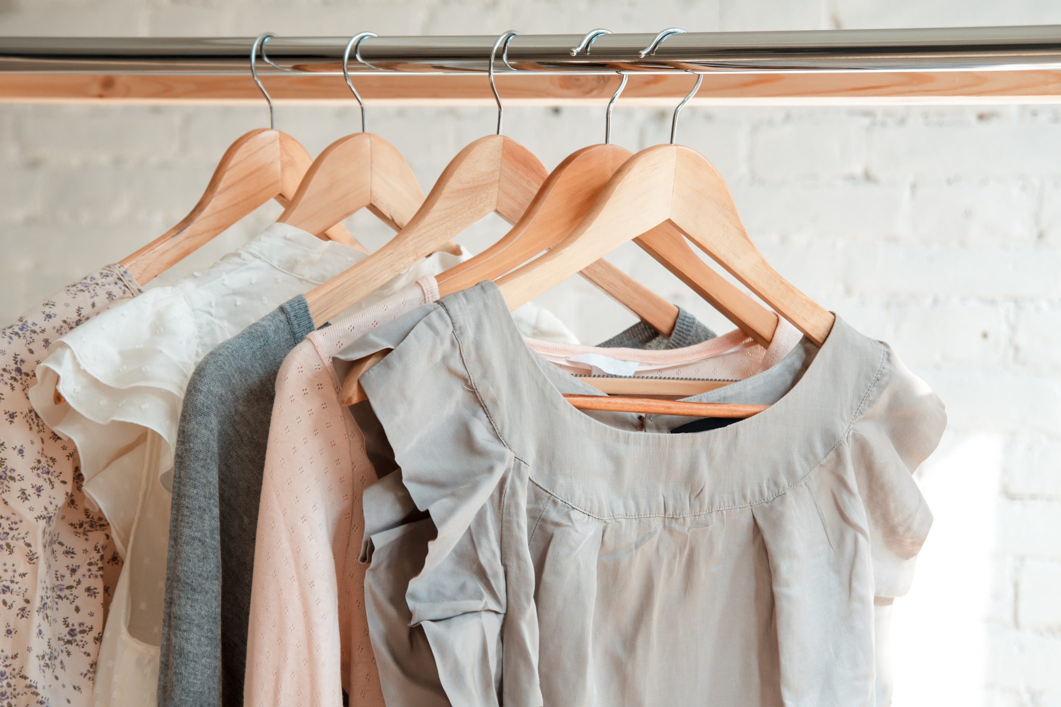 A row of clothes hanging on wooden hangers.